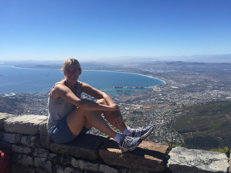 Freudestrahlend genießt die Bloggerin Barbara auf einem kleinen Felsvorsprung die wundervolle Aussicht vom Maclears Bacon Plateau des Tafelbergs in Südafrika.