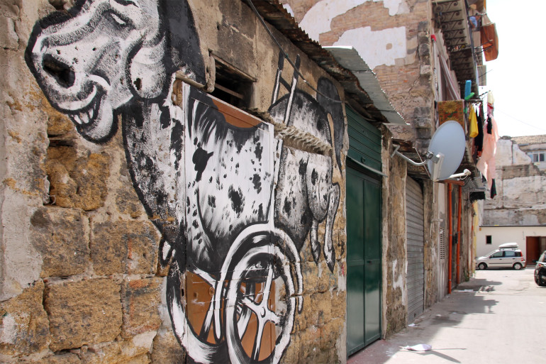 An einer heruntergekommenen Mauer eines Schuppens mit Wellblech in Palermo wurde ein Graffiti gezeichnet.