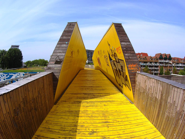 Eine gelbe Holzbrücke namens Luchtsingel steht in Rotterdam und führt zu Mehrfamilienhäusern.