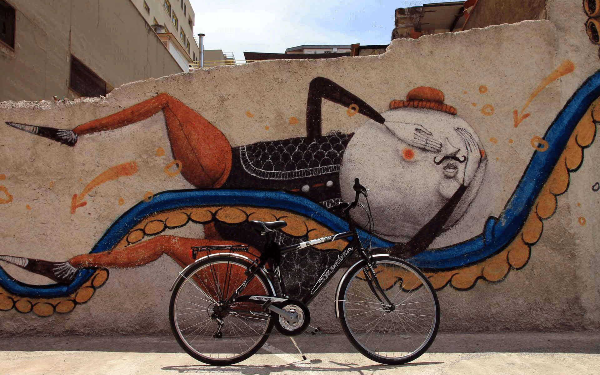 An einer gebrochenen mit Street Art verzierten Hausmauer lehnt ein Fahrrad. l