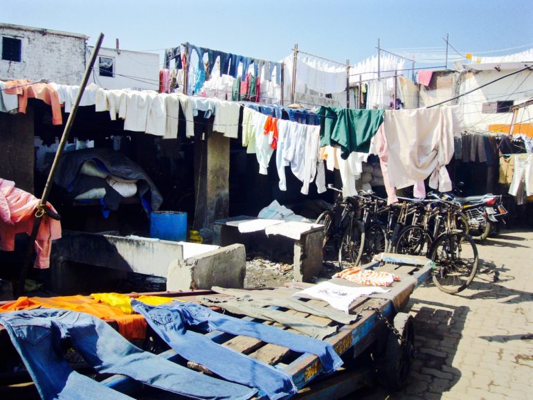 Im Outdoor Waschsalon Dhobi Ghat in Mahalaxmi, Mumbai, liegen auf Holzbrettern und hängen auf vielen Wäscheleinen Wäschestücke zum Trocknen.
