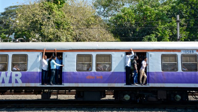 In Mumbai stehen Einheimische in den geöffneten Zugtüren des blau-weißen Western Railways.