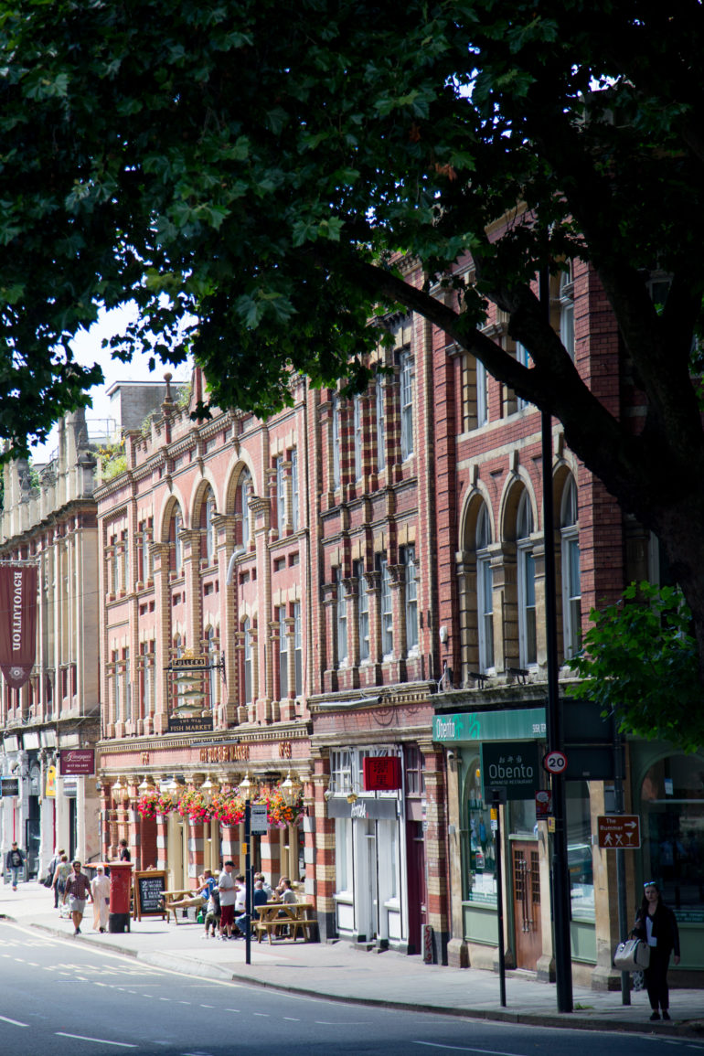 In der Altstadt von Bristol sind die Hausfassaden in rötlicher Farbe getaucht und mit verzierten Rahmen um die hohen Fenstern.