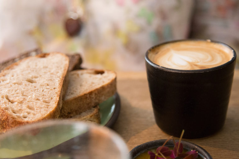 Auf einem Tisch im Mad & Kaffe in Kopenhagen wurde Brot und ein Cappuccino mit einem Milchschaumherz angerichtet.