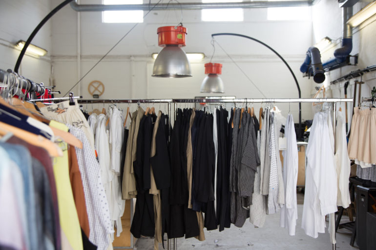 In einer Modebotique in Kopenhagen hängen Kleidungsstücke an einer Kleiderstange.