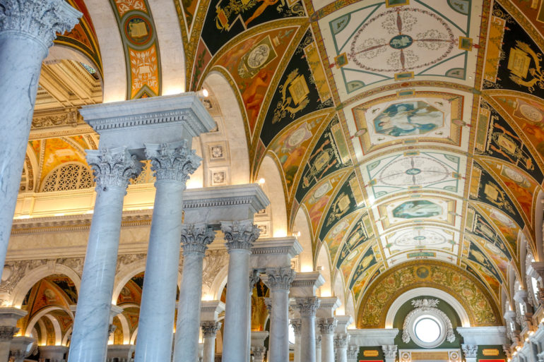 Ein Blick auf die Decken der Library of Congress in Washington D.C. zeigt auf Marmorgestützte Kuppeln verziert mit goldenen, schwarzen und roten Verzierungen.