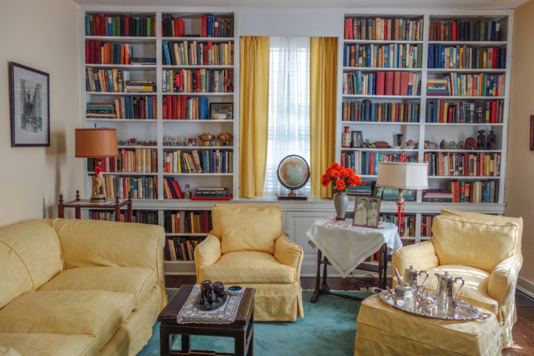 Im Wohnzimmer des Marshall House in Virginia, USA. steht eine gelbe Sitzgarnitur mit gefüllten Bücherregalen, sowie kleinen Tischchen mit Lampen darauf.