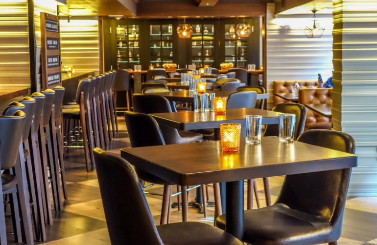 In Washington D. C.`s Restaurant und Cocktailbar Radiator befinden sich verschiedene Sitzmöglichkeiten in braunem Leder und Holz gehalten, an den Tischen wurden kleine orange Lichter gedeckt.