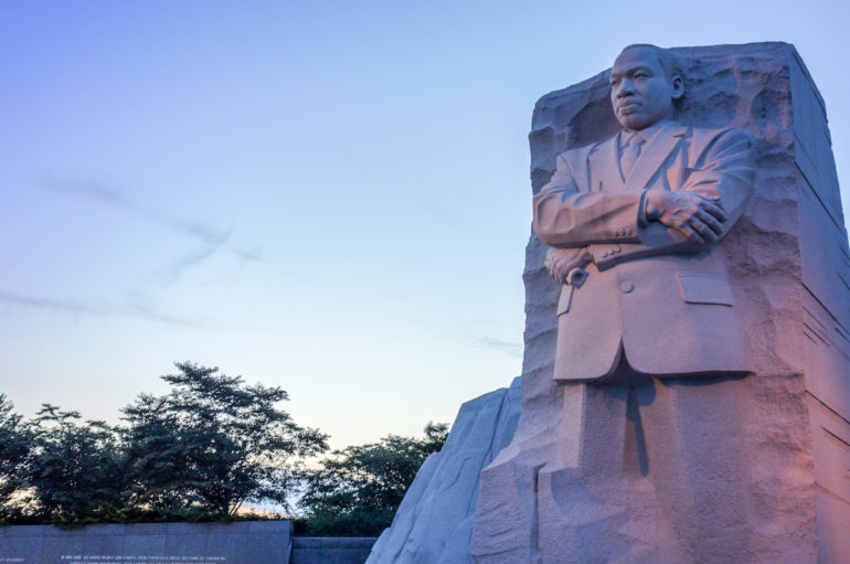 Bei Sonnenuntergang strotzt in riesiger Größe die aus Stein gemeisselte Statue von Martin Luther King mit festem Blick und verschränkten Armen in Washington D. C., USA.