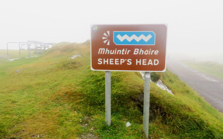 Auf einem kleinen Wiesenhügel steht im Nebel das braune Sheep´s Head Schild, das den westlichsten Punkt der Halbinsel markiert.
