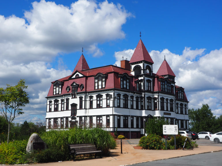 Die weiße Lunenburg Academy in Kanada wirkt von ihrer Architektur wie eine Burg, mit roten Spitztürmchen und dunkelbraunen Fensterrahmen.