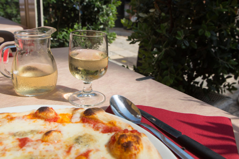 In einem Restaurant in Vieste, Apulien werden Pizza und Weißwein serviert.