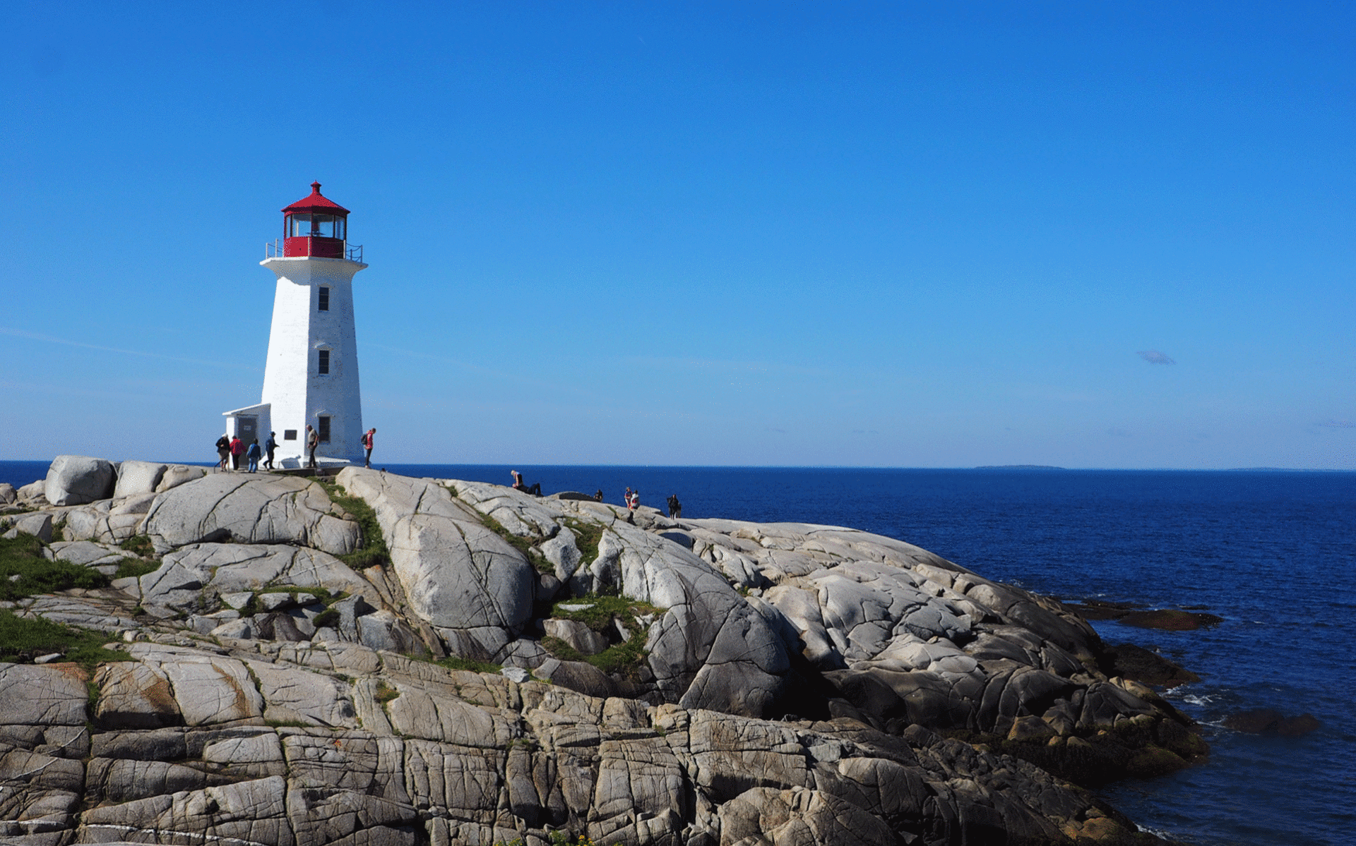 Ein weiß-roter Leuchtturm stehet auf einem Felsvorsprung am Meer von Nova Scotia, Kanada.