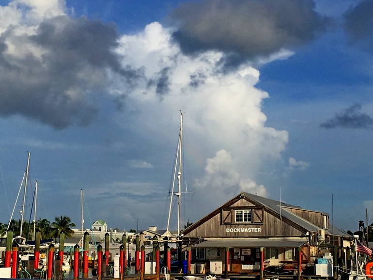 Am Hafen von Key West sind Boote und Schiffe an roten Pfosten angeseilt, das Häuschen des Dockmasters ist aus dunklem Holz.