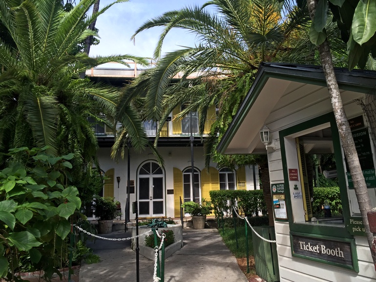 Das Haus des berühmten Schriftstellers Ernest Hemingway im Kolonialstil und mit gelben Fensterläden versteckt sich hinter Bäumen und Palmen bei Key West, Florida USA.
