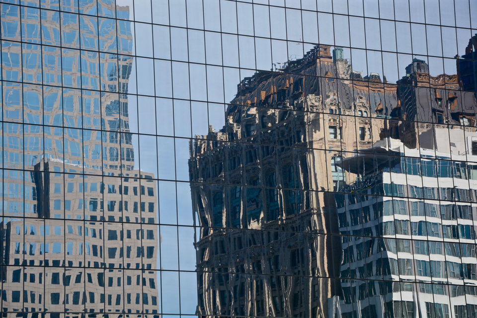 The art deco skyscrapers and glittering skyscrapers of the city of New York are reflected in the windows of a skyscraper.