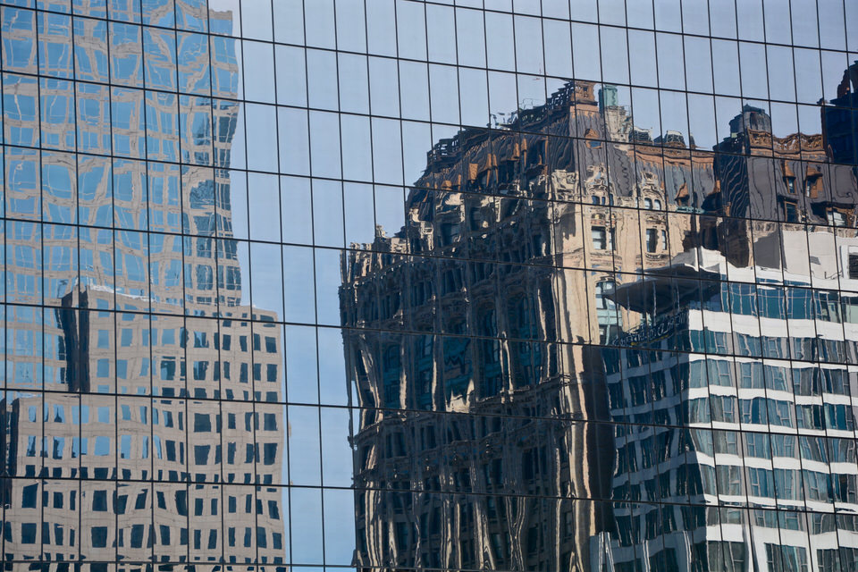In den Fenstern eines Wolkenkratzers spiegeln sich die Art-Deco-Hochhäuser und glitzernden Wolkenkratzer der Stadt New York.