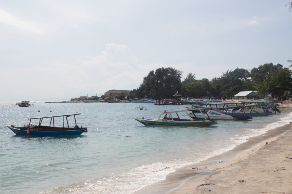 Am Sandstrand der Insel Gili Air auf Indonesien haben kleine Fischerboote geankert.