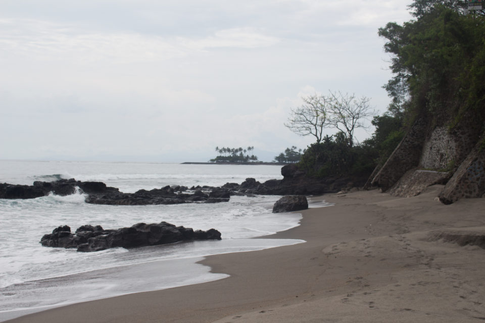 An Lomboks Strand Senggigi ist der Sand dunkler und schwarze Steine ragen aus dem Meer.