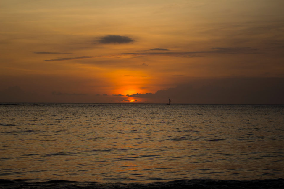 Der Sonnenuntergang von Lomboks Senggigi Beach taucht den Horizont in ein warmes orange-braunes Licht.