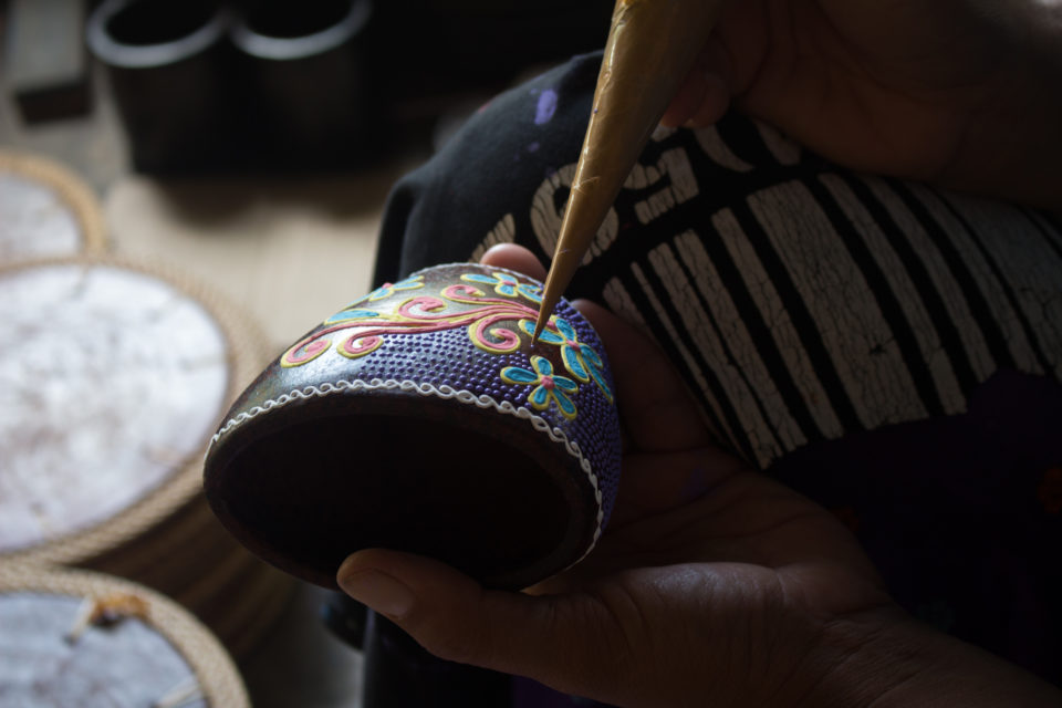 In einer Töpferei im Süden Lomboks verziert ein Handwerker seine Töpferkunst mit einer Art Spritztülle zu feinen Malereien.