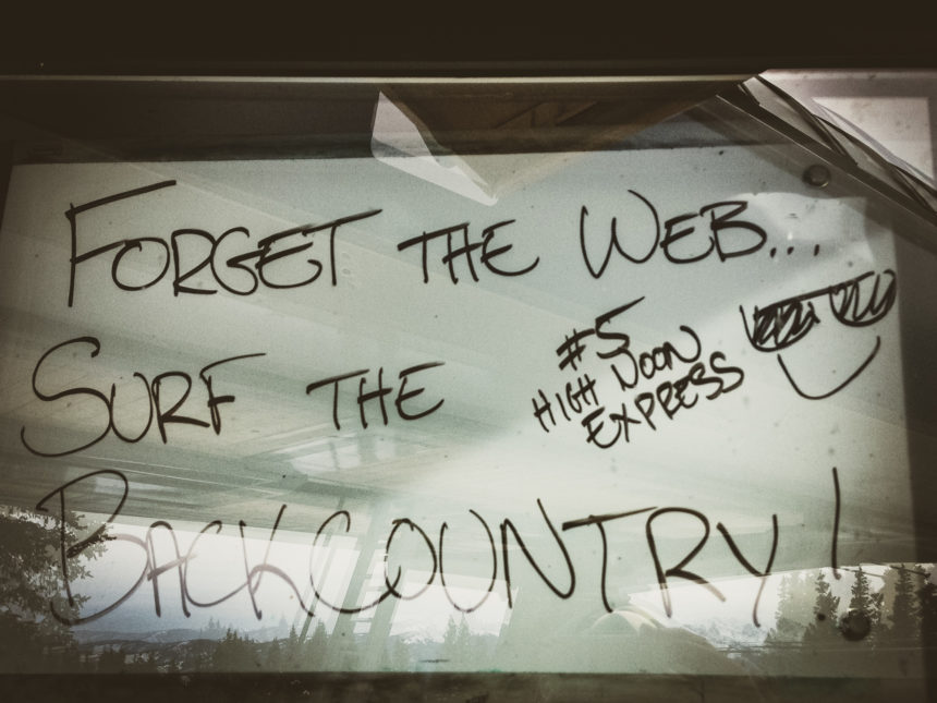 Auf einem Schild mit Verglasung nahe einer Skipiste in Vail, USA, wurde handschriftlich der Hinweis "Forget the web, surf the Backcountry" geschrieben.