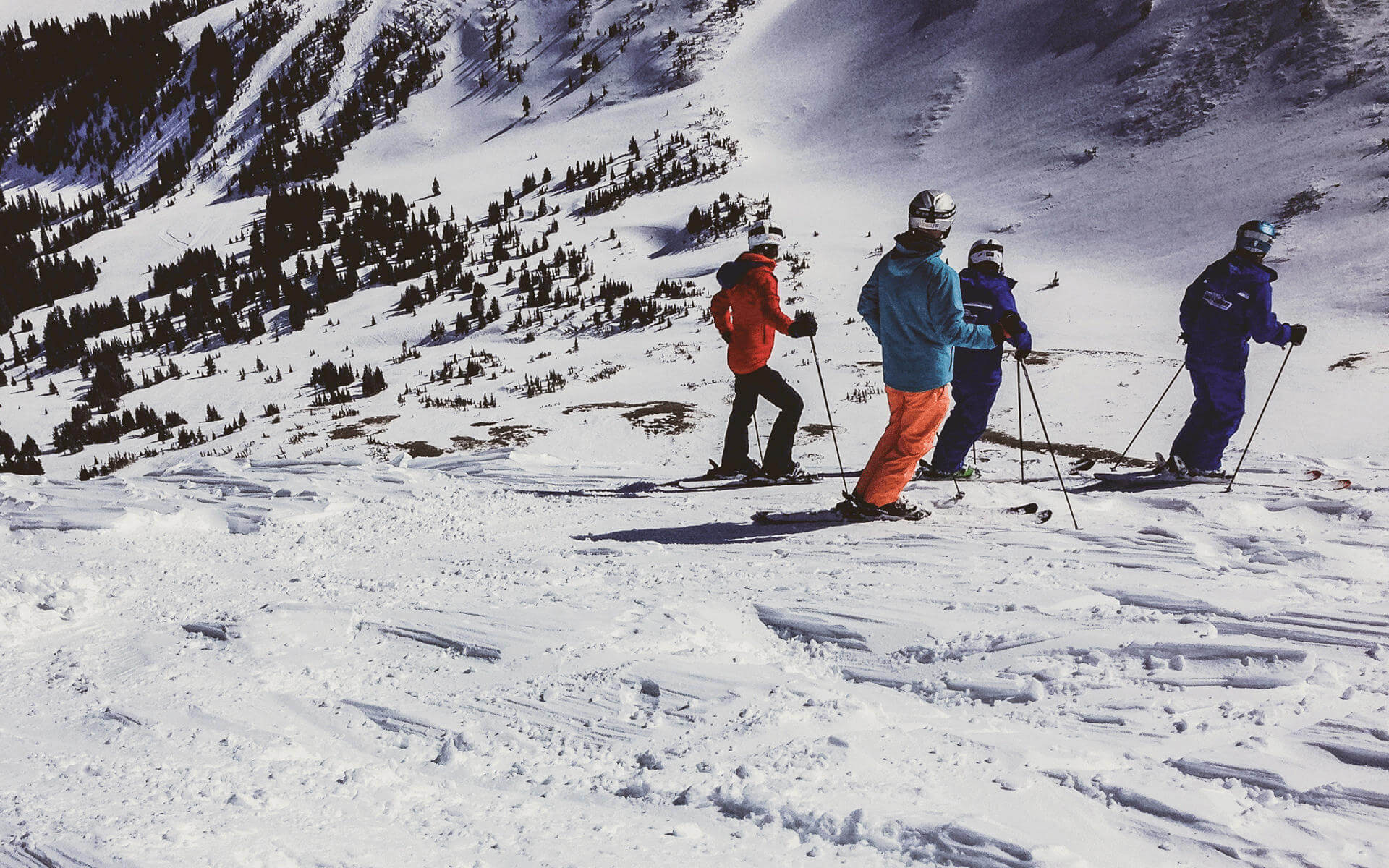 Vier Skifahrer stehen auf einer Skipiste in den USA und blicken den Hang hinab.