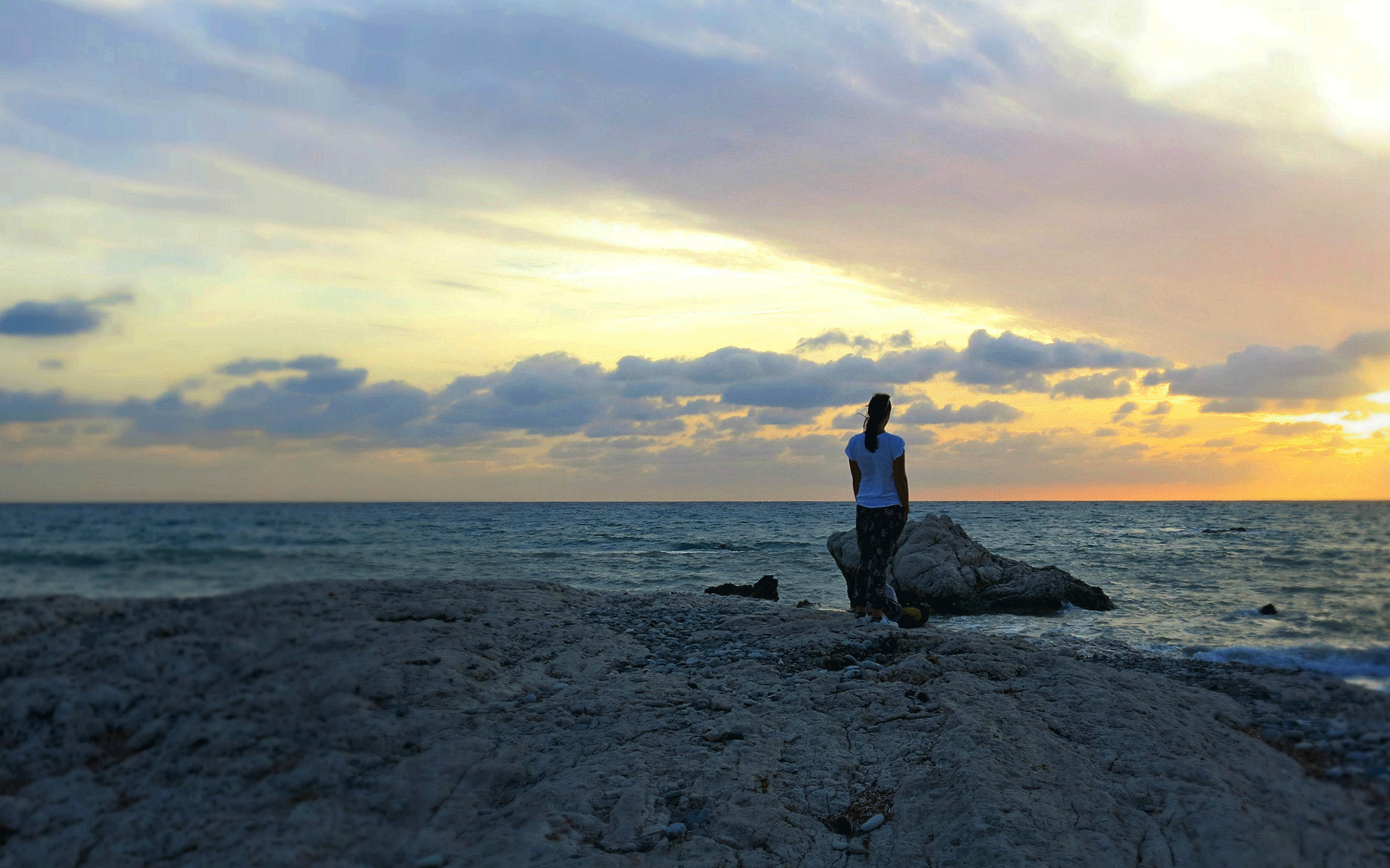 Reisebloggerin Eva genießt am Aphrodite-Strand Petra tou Romiou in Zypern den Sonnenuntergang über dem Meer.
