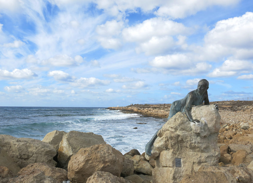 Die Aphrodite Statue auf einem Felsen an der Küste von Paphos auf Zypern, das Meer schlägt leichte Wellen.