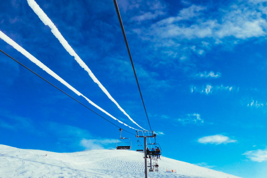 Unter strahlend blauem Himmel fährt ein Sesselift entlang einer kanadischen Skipiste.