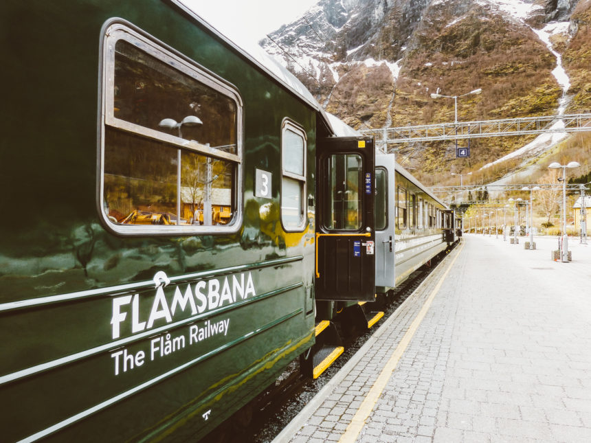 An einem Bahnhof in Norwegen stehen grüne Wagons der Flåmsbahn.