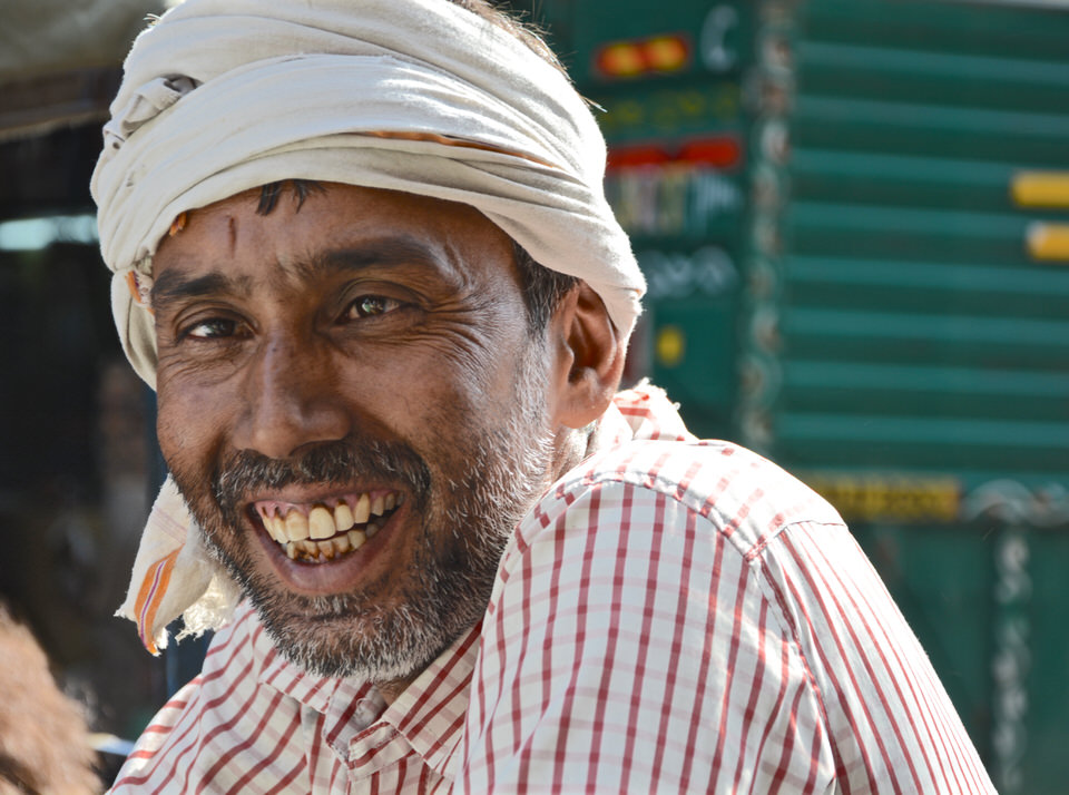 Ein einheimischer Rikschafahrer mit Turban lächelt in Delhi am Chawri Bazar in die Kamera.