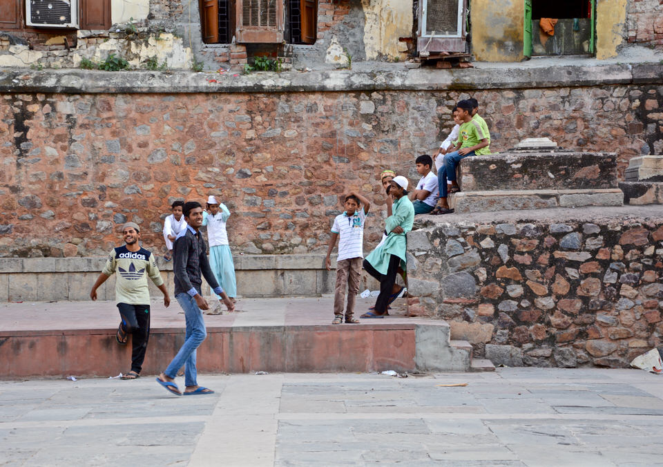 In Delhi, Hazrat Nizamuddin spielen junge Einheimische neben den alten steinernen Grabmalen.