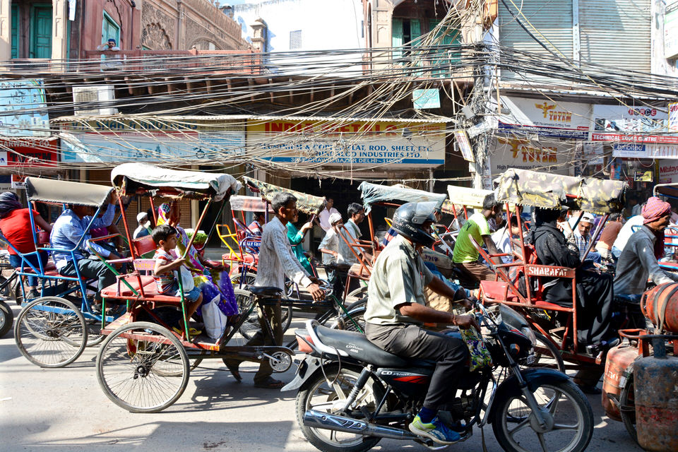 Auf den Straßen von Old Dehli, Chowri Bazar, stehen viele bunte Rikscha- und Motorradfahrer.