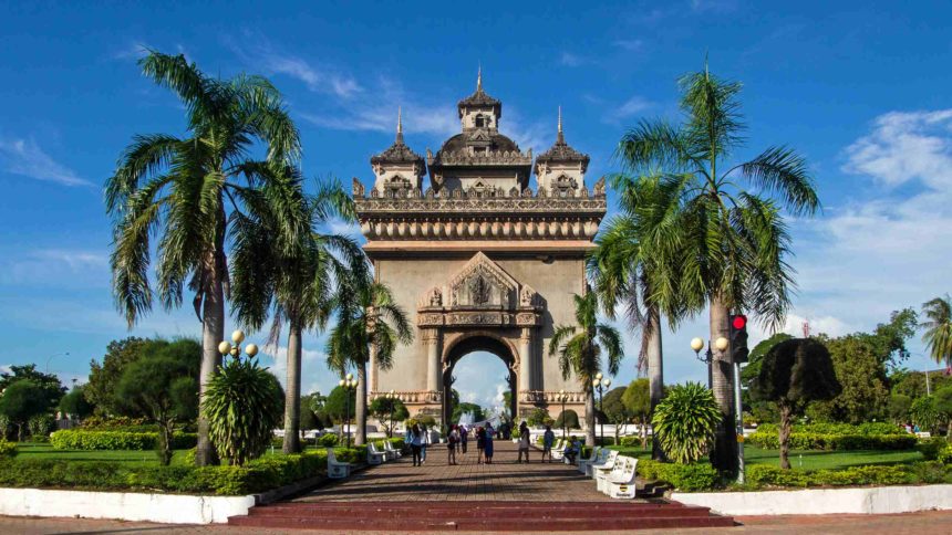 Der von Palmen eingerahmte Triumphbogen Patuxai befindet sich in Laos Hauptstadt Vientiane, 3 verzierte Türmchen schmücken seinen Bogen.