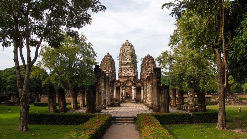 Der Wat Sri Sawai Tempel in Thailand weist drei gut erhaltene Tempeltürme auf und befindet sich inmitten von schattenspendenden Bäumen.