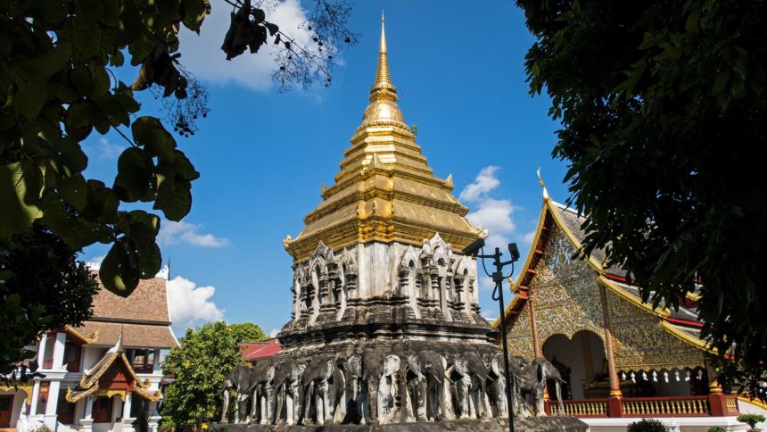 Der Wat Chiang Man in der Altstadt von Chiang Mai trägt ein goldenes Dach , am Sockel verzieren Elefantenköpfe aus Stein den Tempel.
