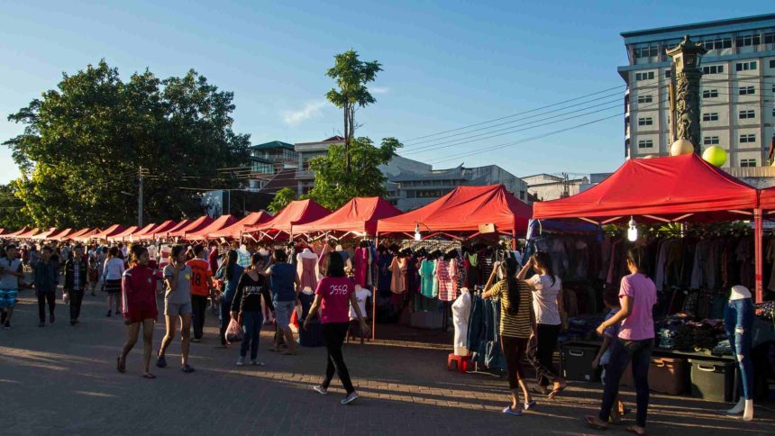 Am Fluss des Mekong in Laos befindet sich der Nachtmarkt am Anouvong Park, hier zieren viele kleine Stände mit roten Schirmen den Weg, zum Verkauf werden alllerlei Souvenirs und Klamotten zum Verkauf angeboten.