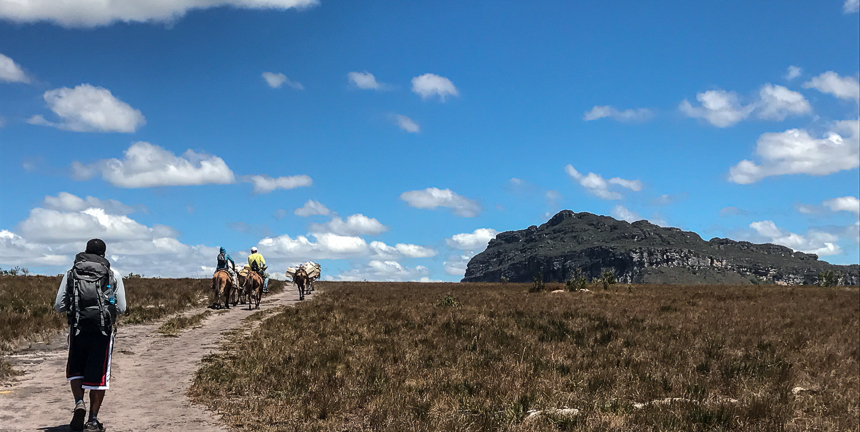 Wanderer zu Fuß und mit Pferden auf dem sandigen Weg zu Vale do Pati in Brasilien.