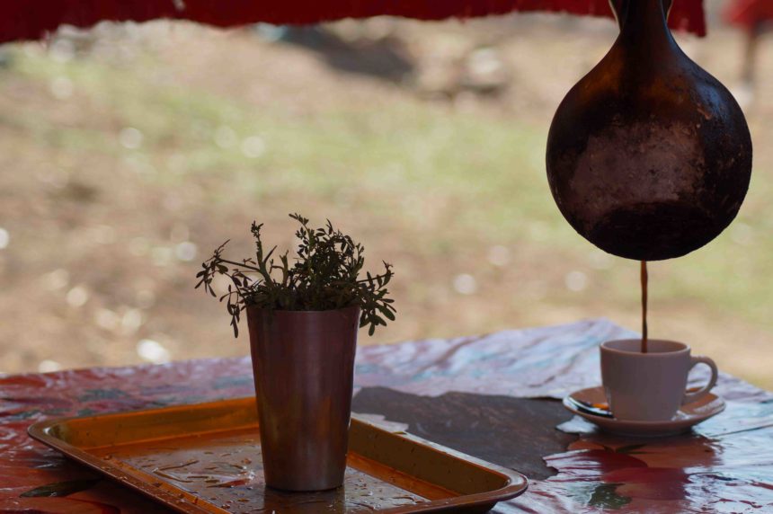 Auf einem Tisch in Äthiopien wird gerade Kaffee in eine kleine Tasse eingegossen.
