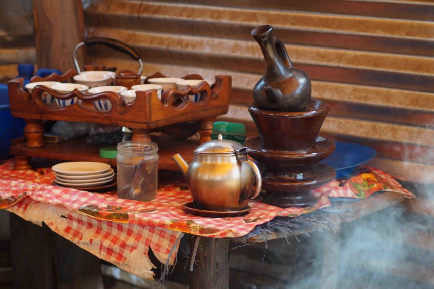 Auf einem Tisch in rot-weißer Tischwäsche stehen verschiedene Gegenstände, die für eine äthiopische Kaffeezeremonie benötigt werden.