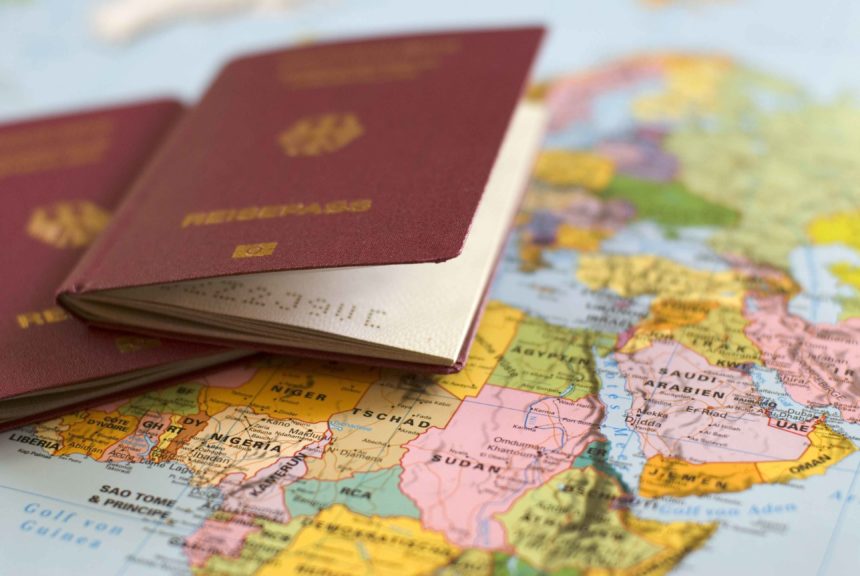 Auf einer Weltkarte liegen zwei Pässe, für die Vorbereitungen einer Weltreise sollte man die Visabestimmungen der Länder berücksichtigen.