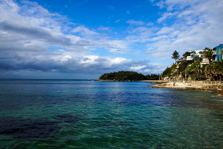 Manly in Australien bietet einen traumhaften Ausblick über türkisfarbenes Meer und Palmen am Strand.