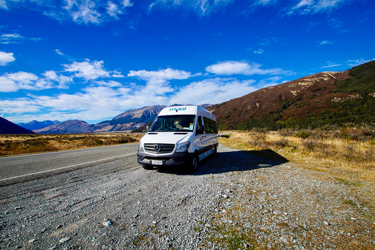 Ein weißer Camper steht einsam, abseits eines Weges auf Schotter mitten im Nirgendwo von Neuseeland.