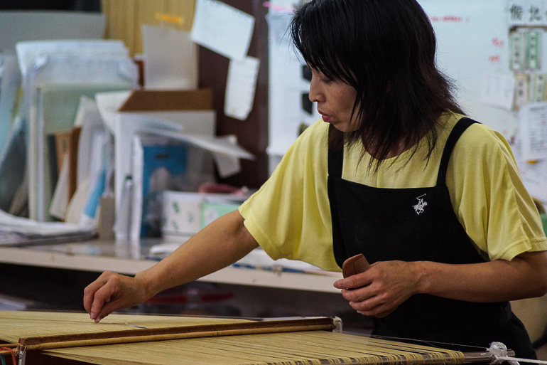 Eine einheimische Weberin in der Minsa Weberei auf der Yaeyama Insel Ishigaki arbeitet konzentriert an ihrem Web-Projekt.