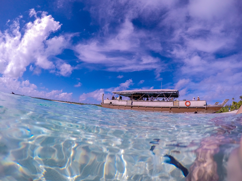 Auf den Cook Inseln ankert ein Boot vor der kleinen Insel One Foot Island.