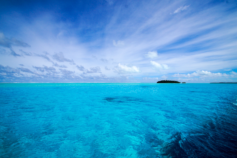 Eine kleine Insel liegt inmitten des glasklarem Meer der Cook Inseln bei Aitutaki, Ozeanien.