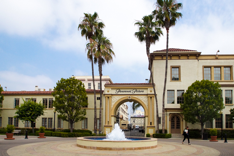 Vor dem Eingangstor zu den Paramount Studios in Los Angeles befindet sich ein Springbrunnen und ist von Palmen umzäunt .