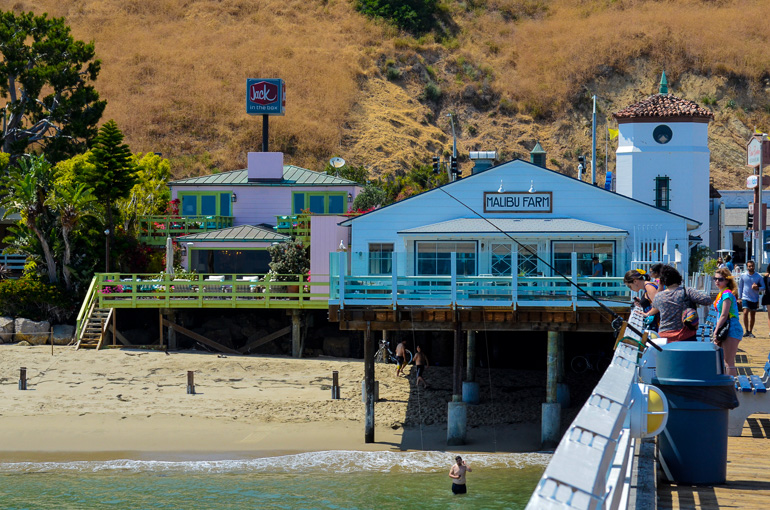 Am Santa Monica Pier in Los Angeles betrachten Besucher das Treiben am Wasser, im Hintergerund ist das Restaurant Malibu Farm zu sehen.