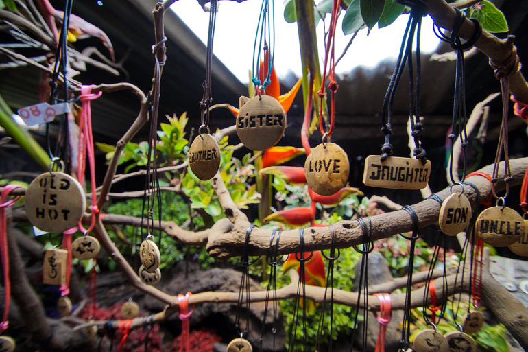 Im Vulkan Pacaya Lava-Store in Guatemala hängen an Ästen verschieden Halsketten mit beschrifteten Lavasteinen und Lederbändern.
